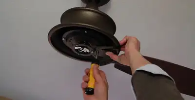 Electrician installing ceiling fan mounting bracket and fixture in Fort Wayne, IN