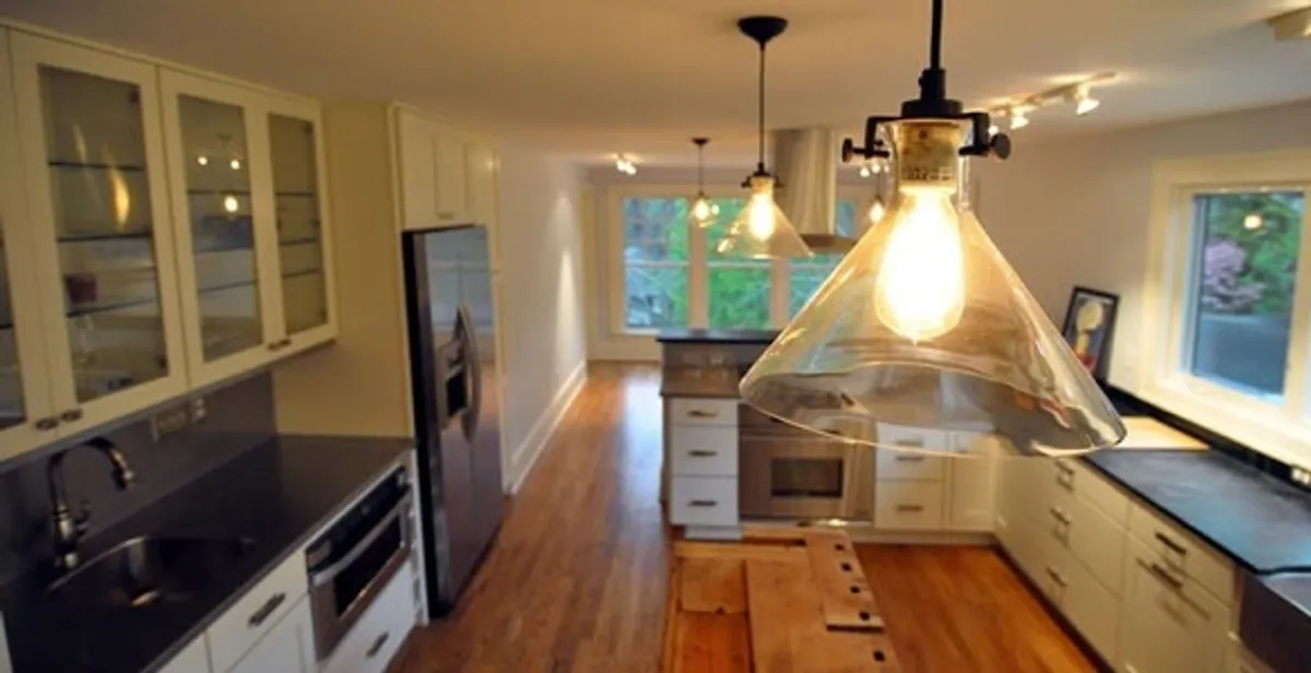 Residential electrician installing modern indoor light fixture in a home in Fort Wayne, IN