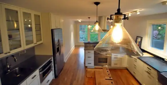 Residential electrician installing modern indoor light fixture in a home in Fort Wayne, IN